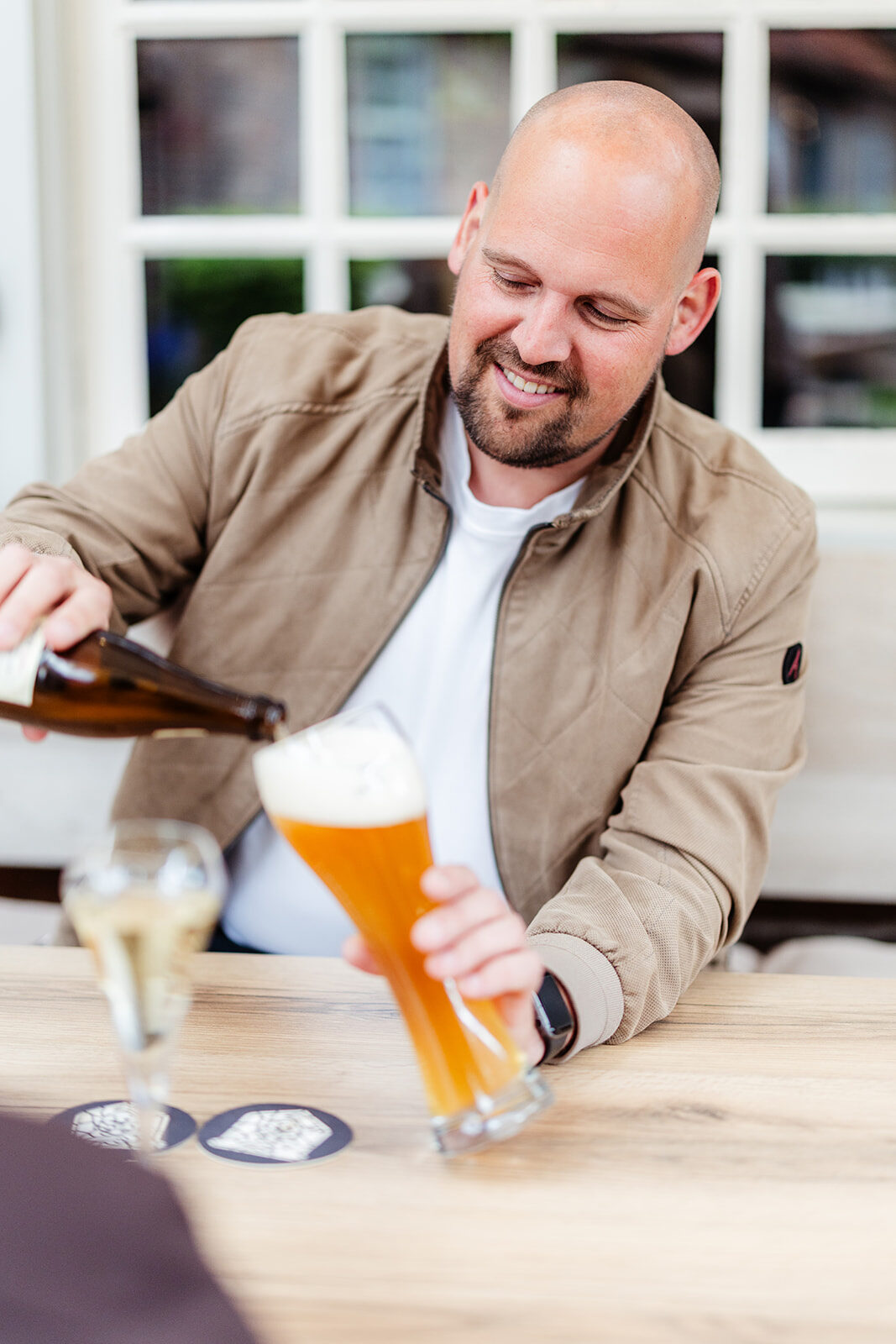 Gast schenkt een speciaalbier in op het terras