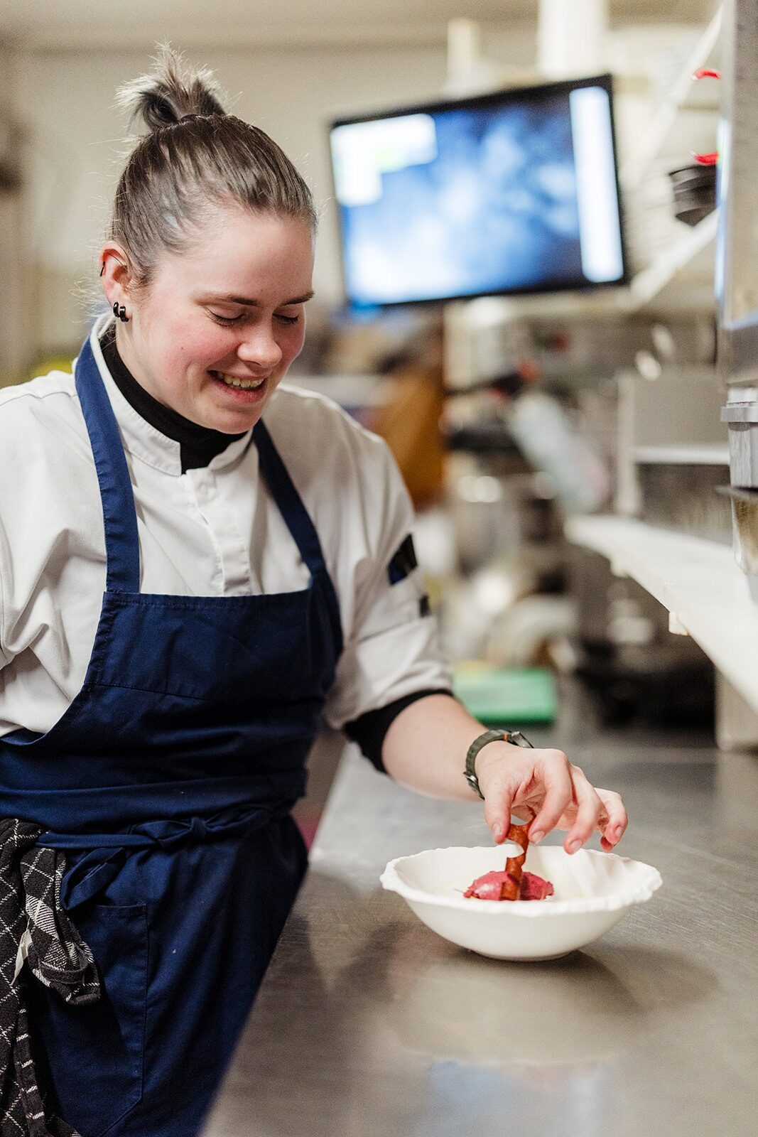 Kok dresseert een gerecht aan de pass in de keuken