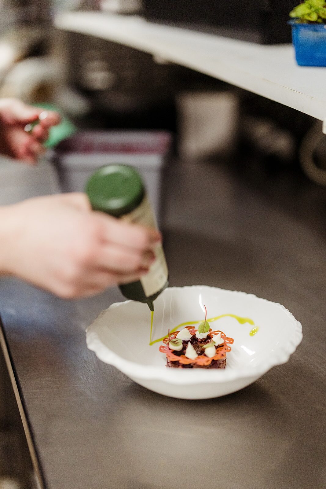 Kok werkt een voorgerecht af met een dressing in de keuken van De Oude Apotheek