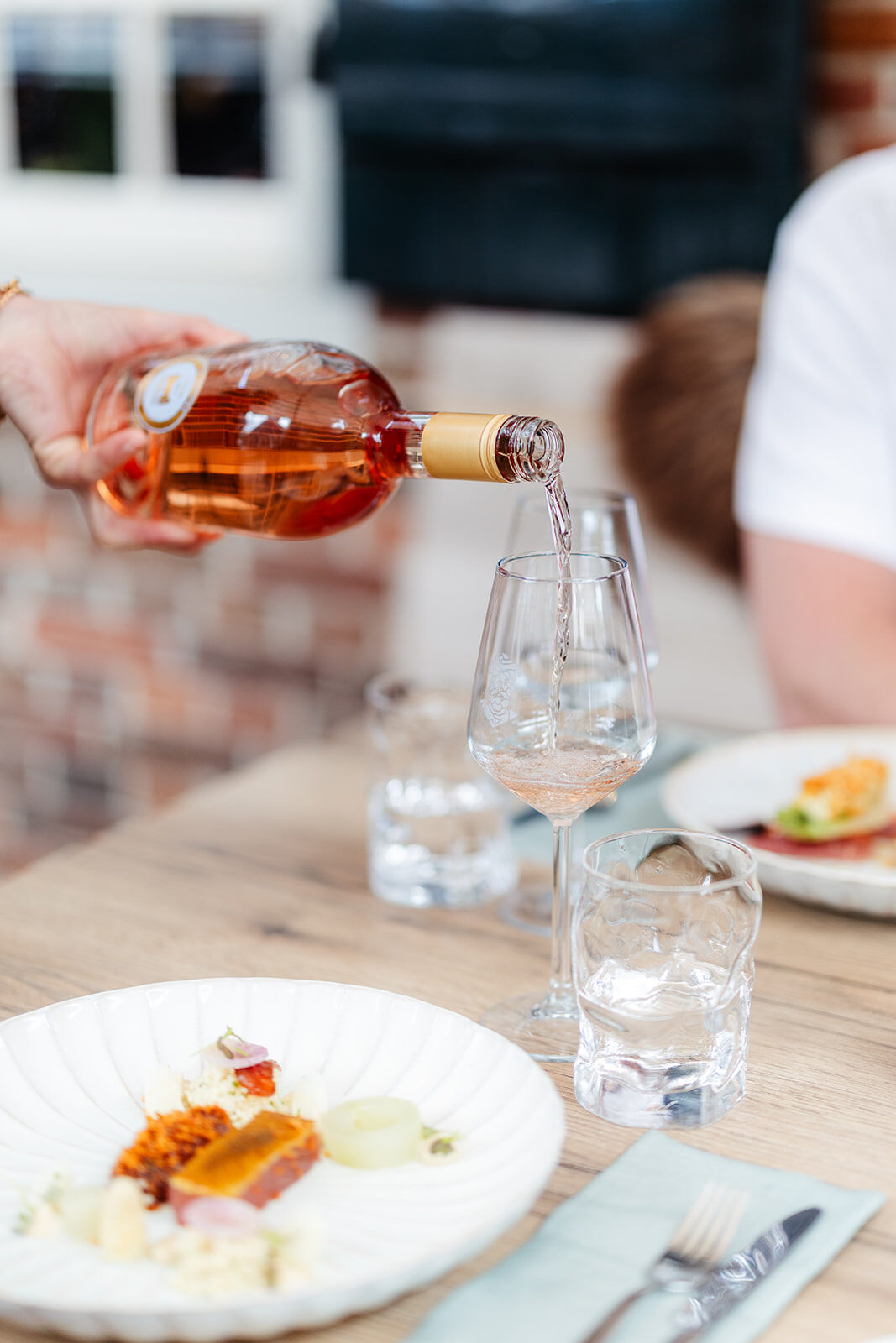 Glas rosé wordt ingeschonken aan een gedekte tafel op het tuinterras